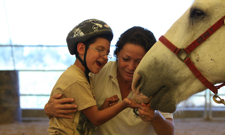 Hipoterapia - chłopiec wraz z instruktorką karmią konia