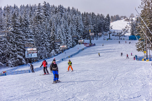 Ludzie zjeżdżający na nartach i snowboardzie ze stoku