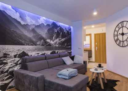 Apartament Koliba na Szymoszkowej Ski Resort - sofa a za nią piękna fototapeta z krajobrazem górskim, podświetlana ledami