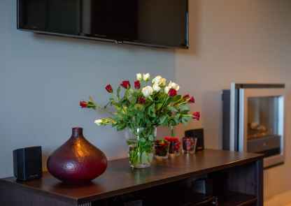 Apartament Bordeaux - szafka a na niej wazon ozdobny i wazon z kwiatami